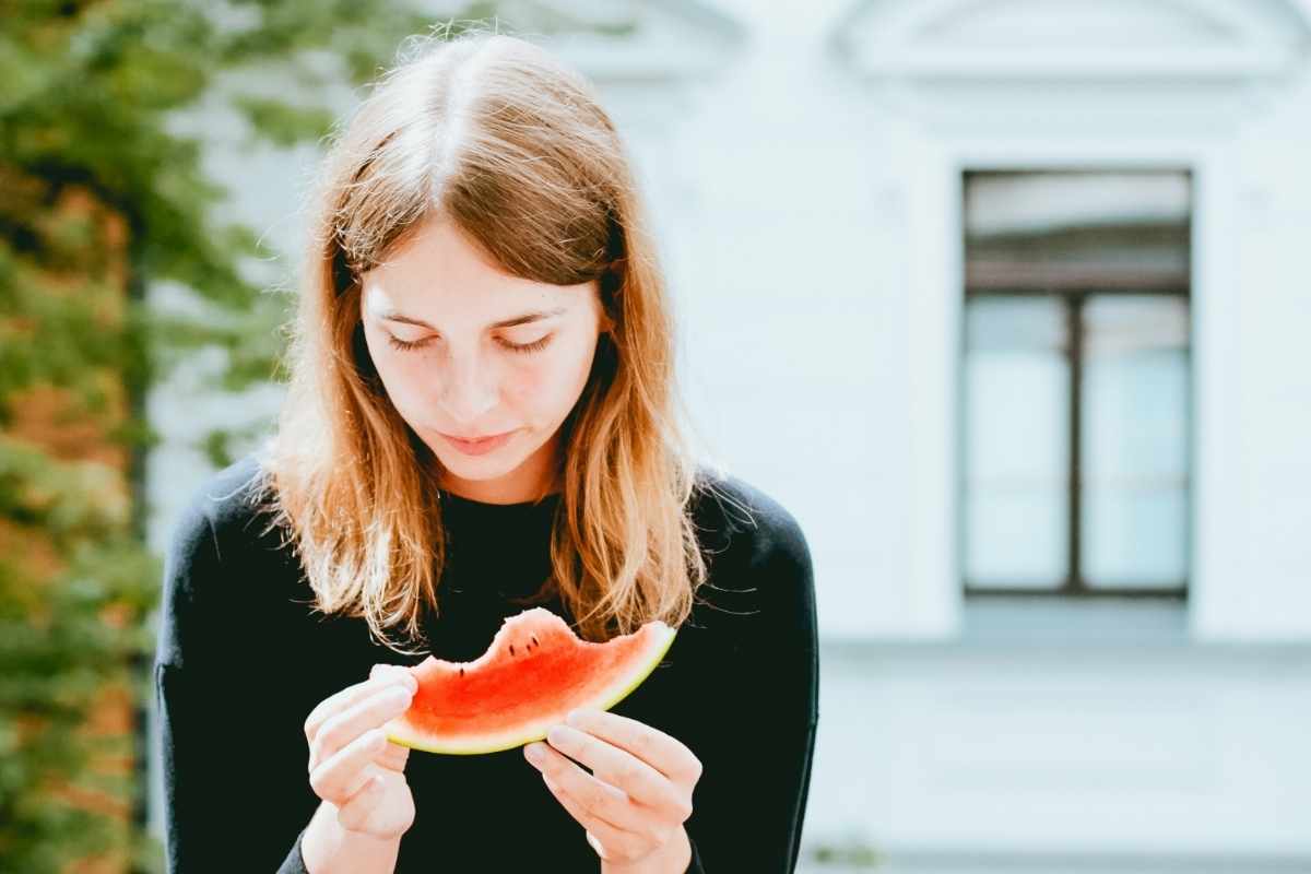 A woman looks at a watermelon. Consider how to improve your relationship with food with Bethany Webster